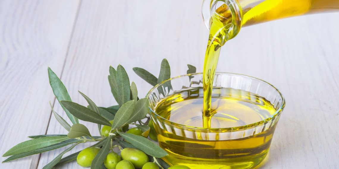 Bottle pouring virgin extra olive oil in a bowl